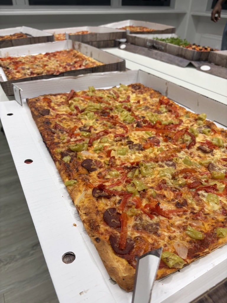 Freshly baked pizza with bell peppers, hot pepperoni, and cheese in an open pizza box, ready for participants of the usd hacking events.