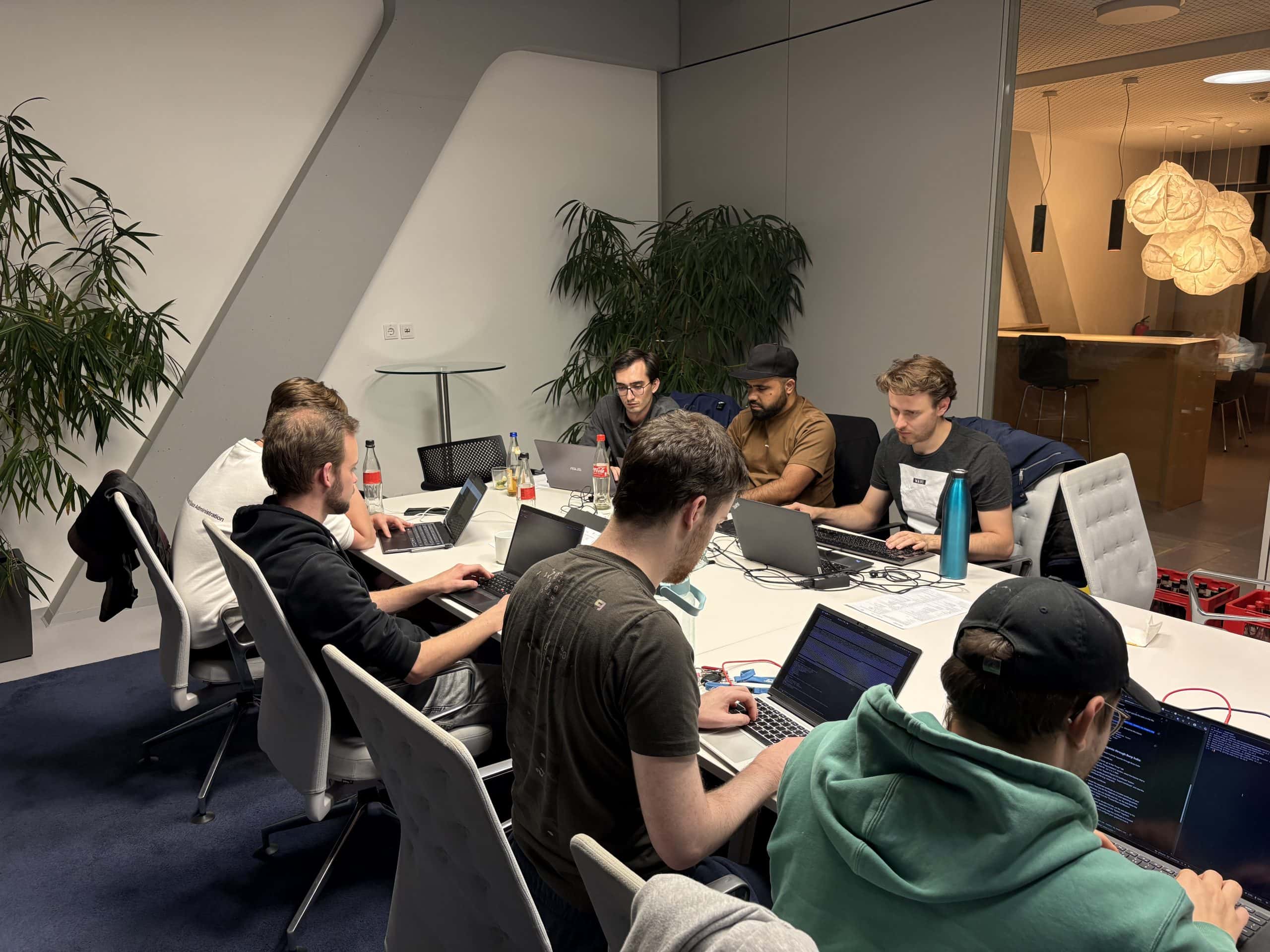 Participants of the usd Hackertage and usd Hacking Night in Munich working intently on laptops in a modern conference room to solve cybersecurity challenges.
